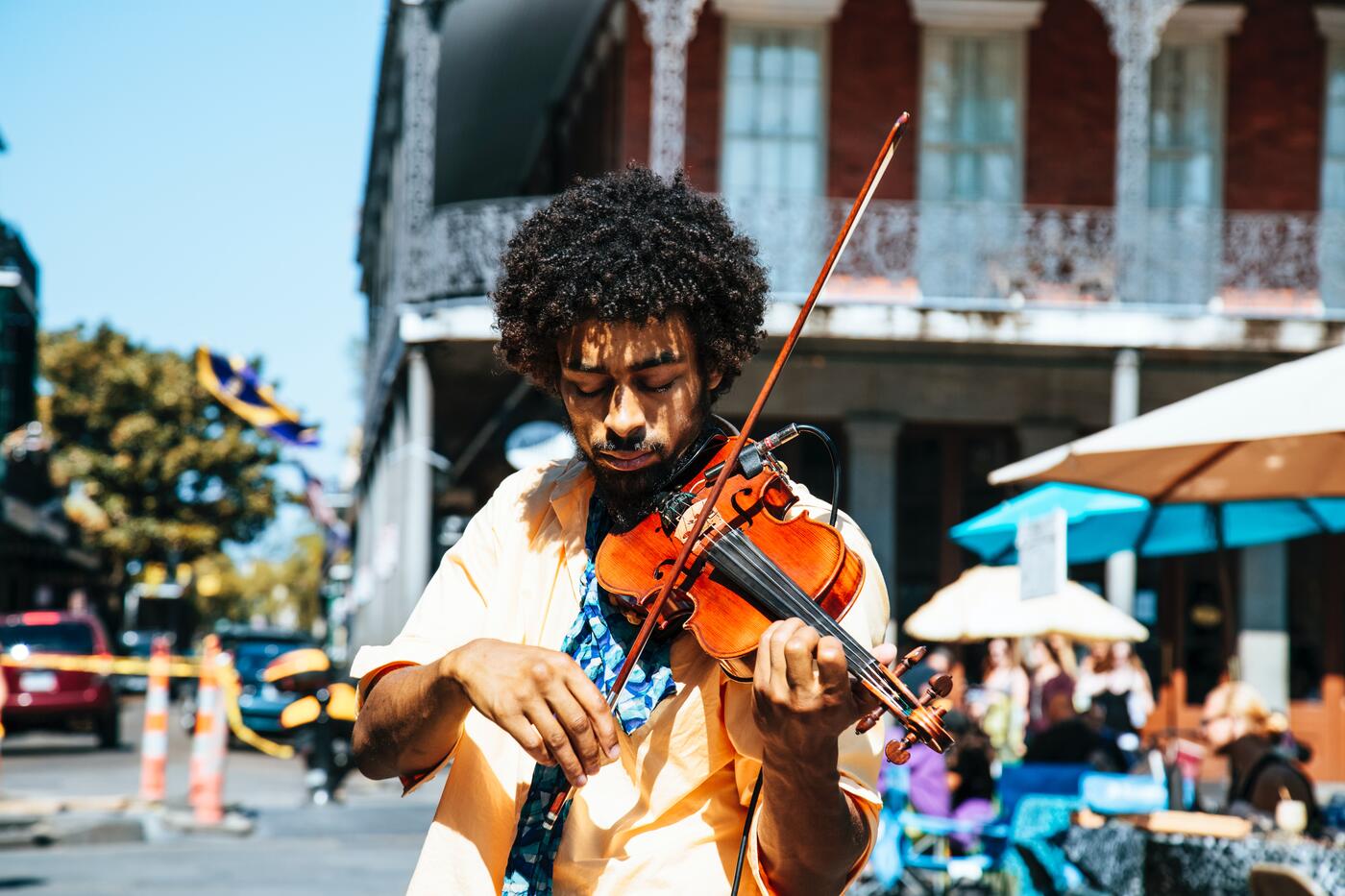 Picture of a man playing a violin with the streets of New Orleans behind him