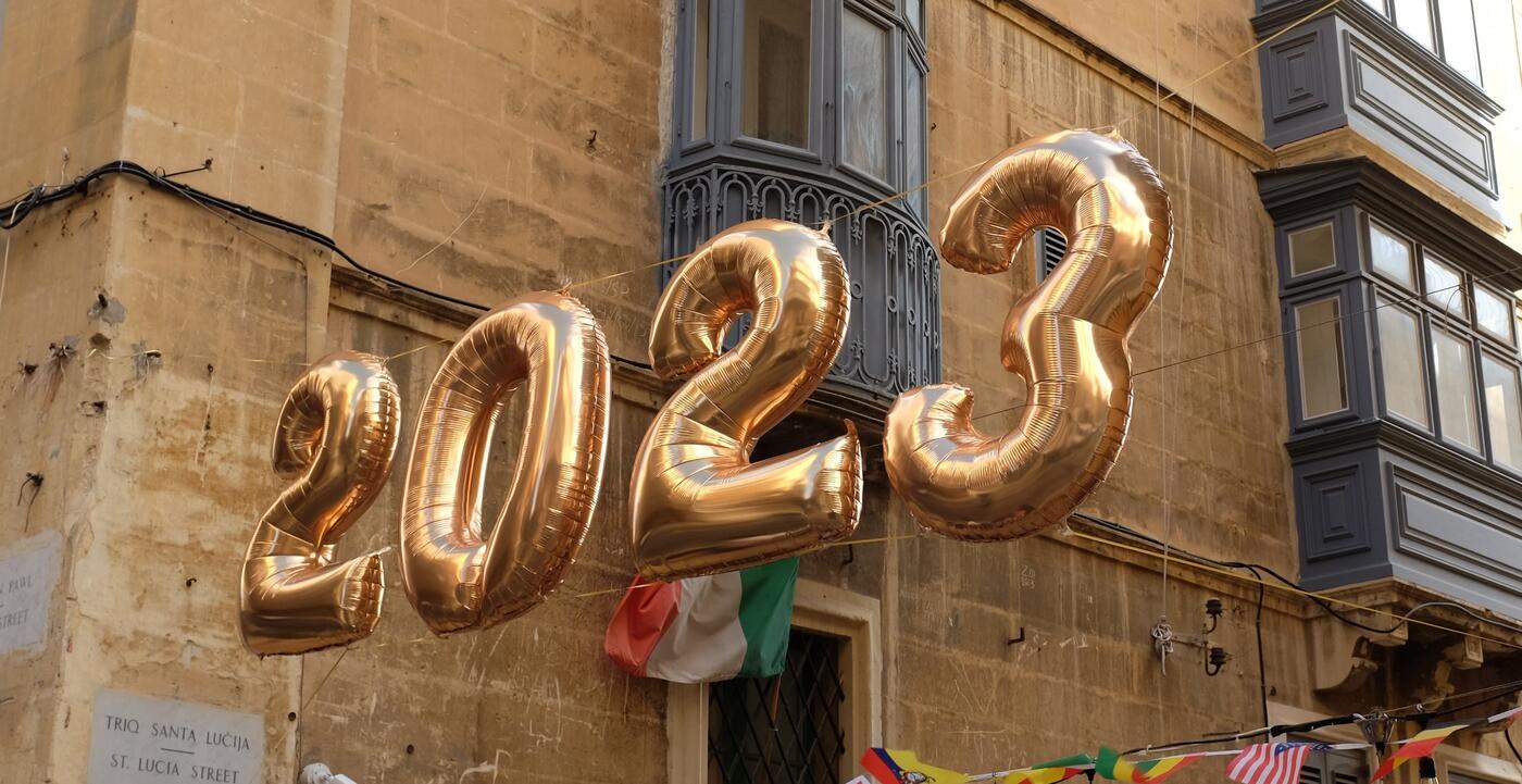 Gold colored balloons in the shape of number "2023" hang in the street